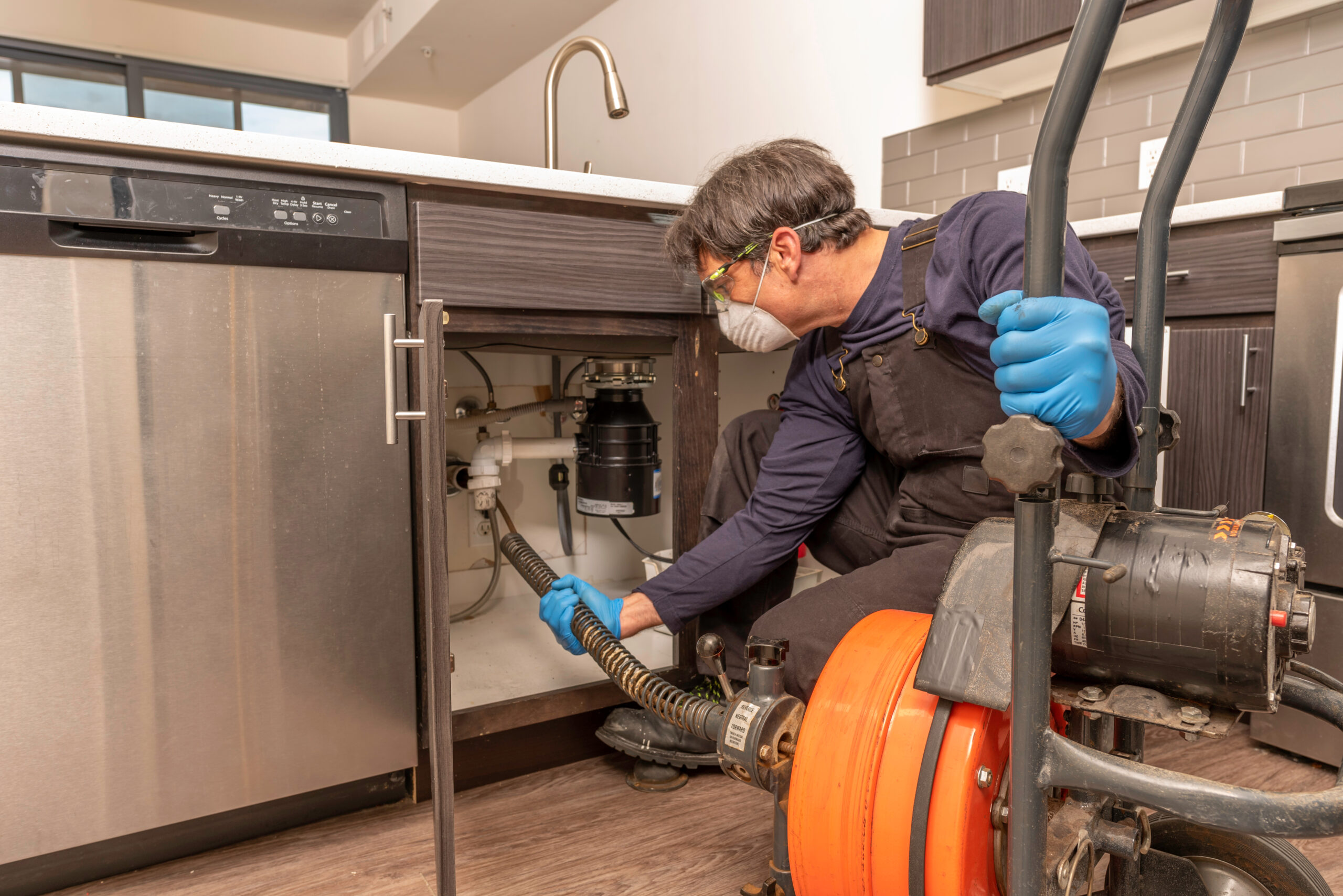 Plumber clearing a clogged household drain